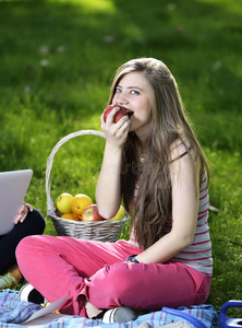 年轻女子在草地上休息，吃苹果