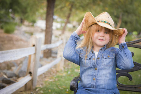 可爱的小女孩戴着牛仔帽在外面摆姿势照相