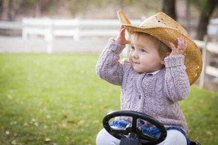 戴牛仔帽在外面玩玩具拖拉机的幼儿