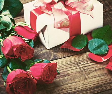 木桌上的红玫瑰和节日礼物