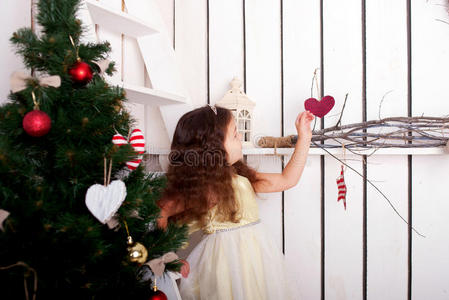快乐的小女孩装饰圣诞树和家。