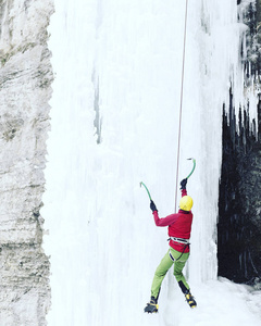攀冰。男子爬冰工具与冰冻的瀑布