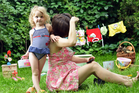 怀孕的母亲和女儿在草坪上玩