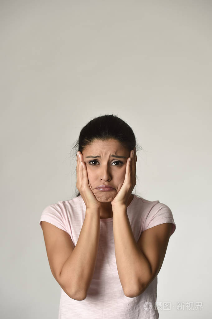 年轻美丽西班牙裔悲伤的女人严重和有关在担心郁闷的面部表情