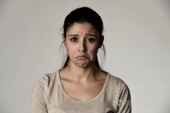年轻美丽西班牙裔悲伤的女人严重和有关在担心郁闷的面部表情