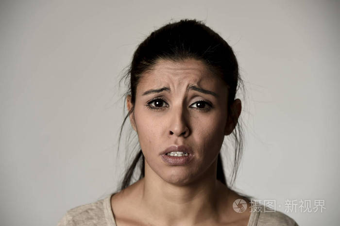 年轻美丽西班牙裔悲伤的女人严重和有关在担心郁闷的面部表情
