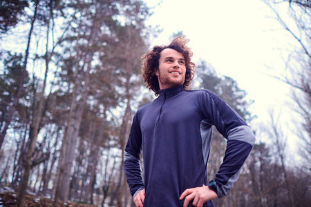 运动型的年轻男子在自然公园树木背景