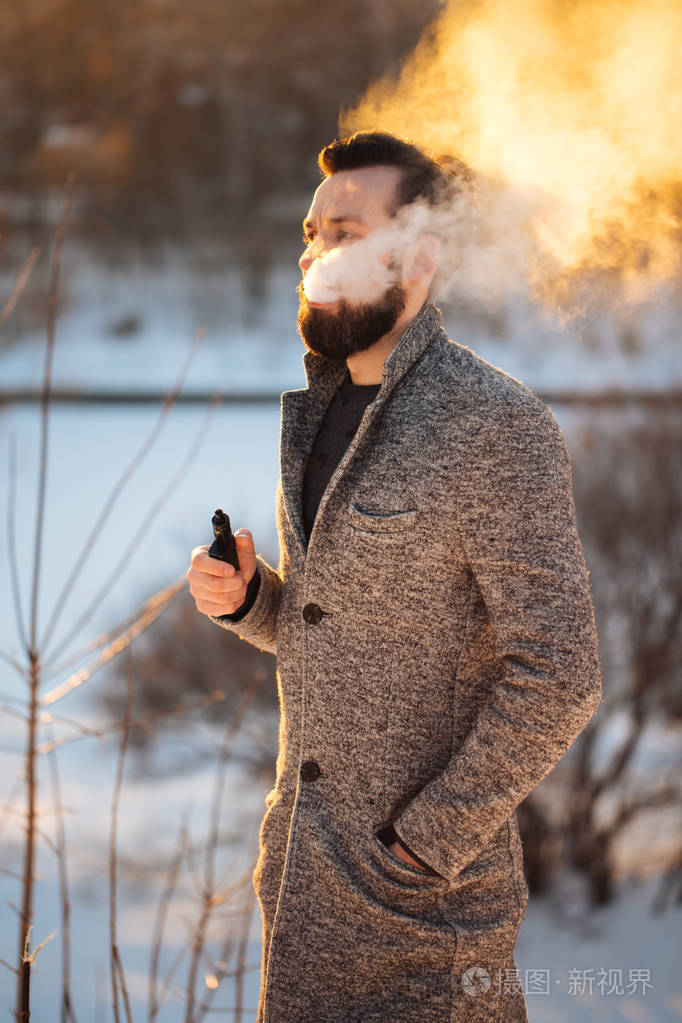 在街头吸烟 vape,vape 蒸汽,蒸汽电子烟的街头时尚年轻的家伙
