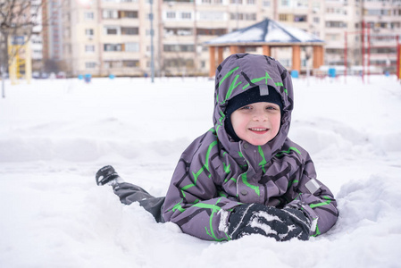可爱的小小孩男孩在多彩冬季服装制作雪天使，躺在。与孩子们在户外活动休闲。快乐的孩子