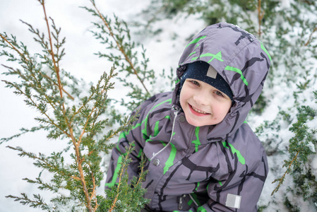 冬天的孩子男孩穿着五颜六色的服装，在户外在降雪的画像。积极的休闲活动，跟在冷的下雪天的孩子。快乐的孩子玩雪