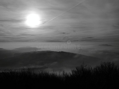 雾蒙蒙的背景增加了山丘。第一缕阳光。黑白照片。