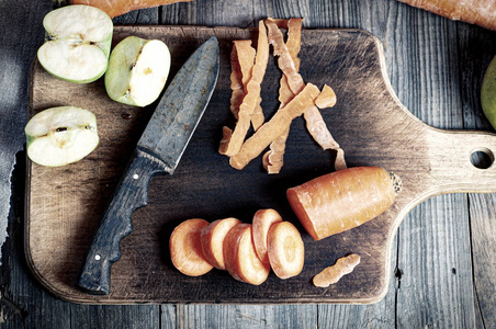 切好的胡萝卜和厨房板上的绿色苹果切成薄片