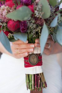 新娘紧握着的红色和绿色婚礼花束