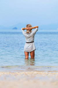 年轻女人站在泰国海滩水中膝盖和欣赏美景