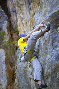 年轻的男登山者，挂在悬崖上用一根绳子