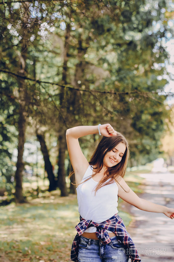 年轻漂亮的女孩步行公园