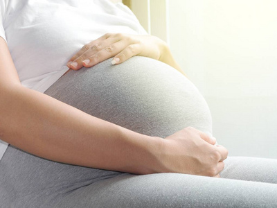 怀孕的妇女，用手在肚子的特写镜头。孕期保健的概念