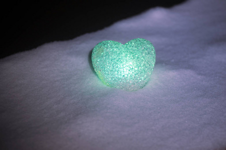 抽象玻璃心脏在雪在晚上。情人节贺卡。绿色的心淡的黑色背景