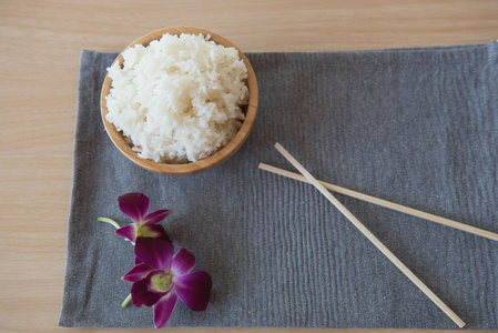 在一个木碗和筷子木背景上的煮好的米饭