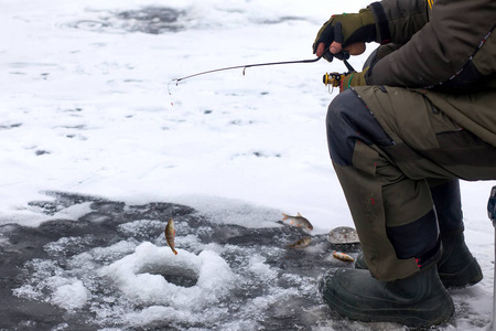 冬季钓鱼抓奖杯户外活动爱好微笑的渔夫在冬天结冰的河捉住鱼冬天钓鱼