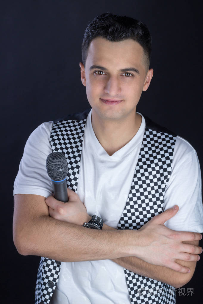 年轻男性的黑头发的流行歌手执行对着麦克风唱歌