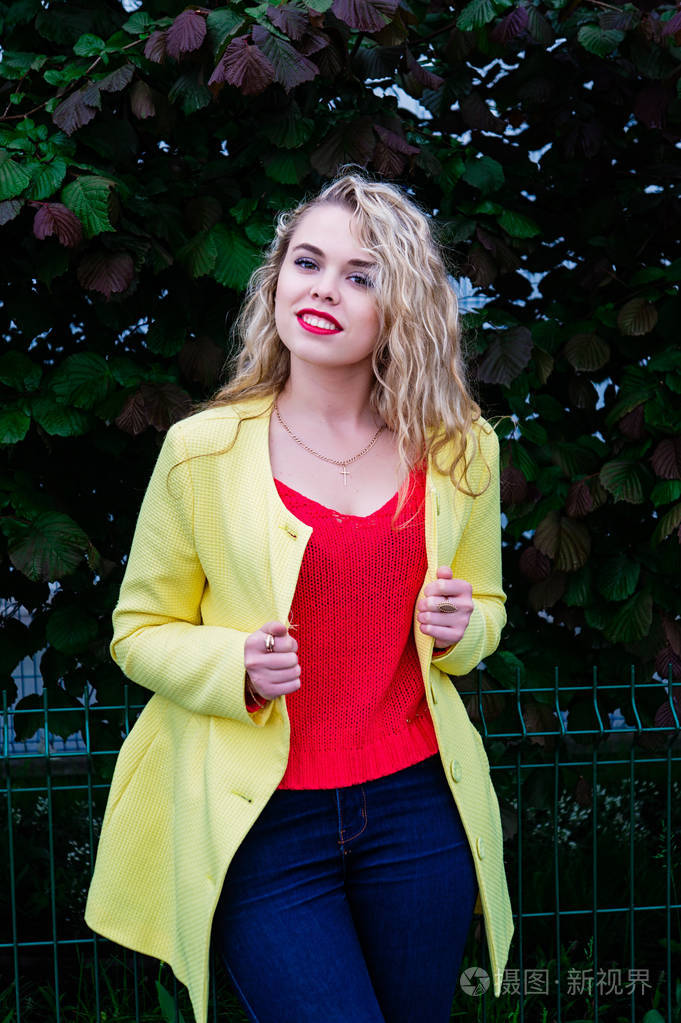在感情上摆在公园的黄色外套迷人金发