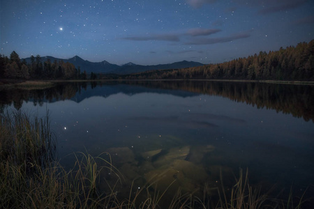 镜子表面湖秋天风景与山脉在早期的黄昏，天空上的星星