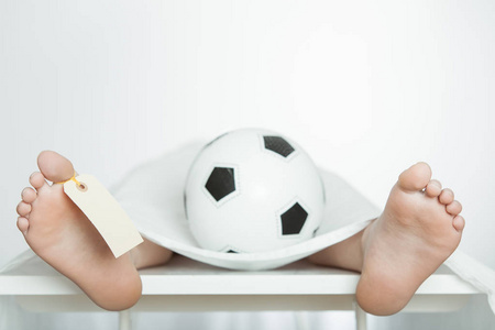 男孩躺在太平间板与足球照片