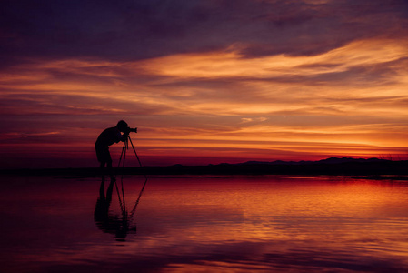 剪影摄影师拍照美丽的海景，日落时在泰国
