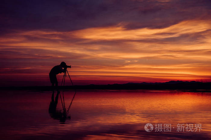 剪影摄影师拍照美丽的海景,日落时在泰国