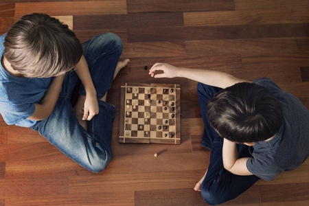 孩子们坐在木地板上下棋。顶视图。游戏 教育 生活方式 休闲概念