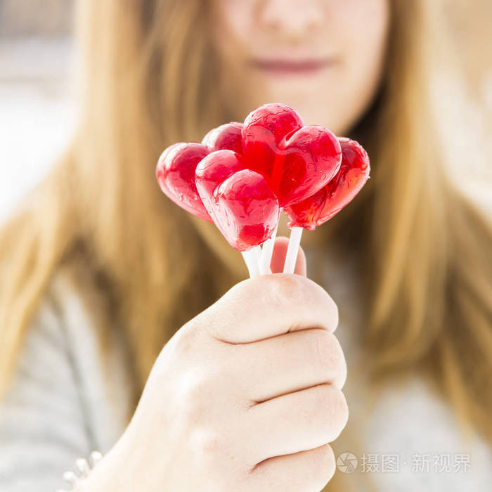 女孩抱着一个红色的棒棒糖在心的形状