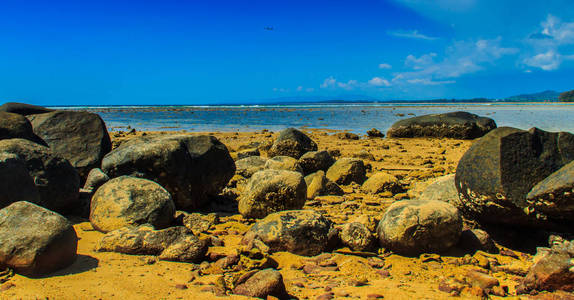 在阴天海水退去时，海滩上美丽的岩石石呈现出戏剧性的蓝天背景。