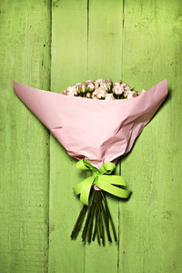 精致的粉红玫瑰的小绿色木背景的花束