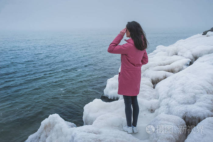 漂亮的女孩向远方眺望大海的岩石上