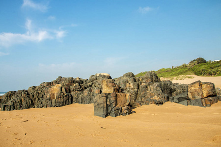 岩石在沙滩和蓝色的沿海天际线