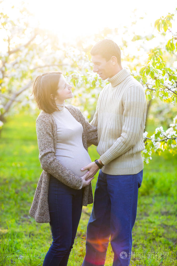 幸福的怀孕夫妇在盛开的花园里
