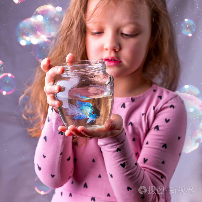 小女婴她抱着蓝色的鱼的鱼缸保健让步
