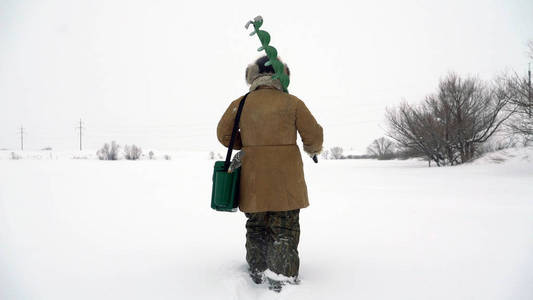 渔夫走在白雪覆盖的湖，寻找好的钓鱼的地方