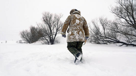 渔夫走在白雪覆盖的湖，寻找好的钓鱼的地方