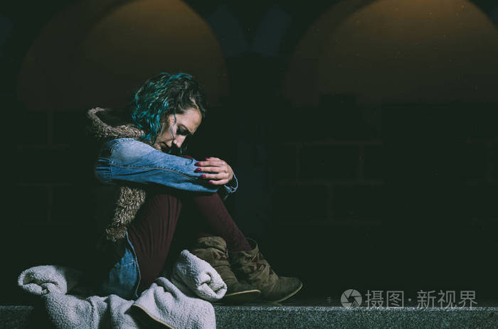 忧郁的年轻女子独自一人坐在它的同时正在下雨