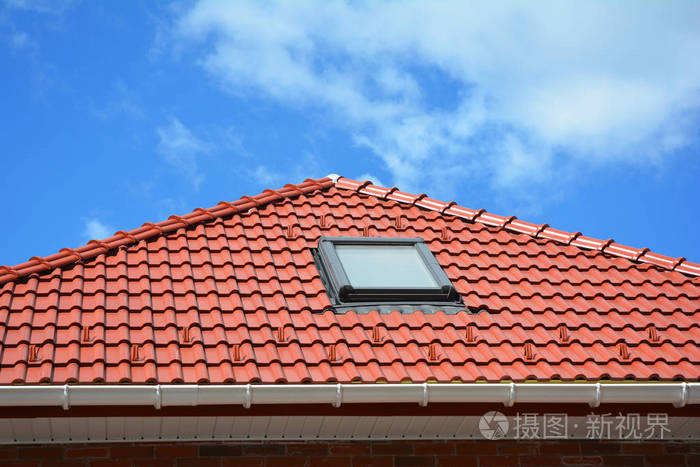 在红色瓷砖上的云天房子屋顶与雨装订线天窗屋顶窗和太阳隧道阁楼的