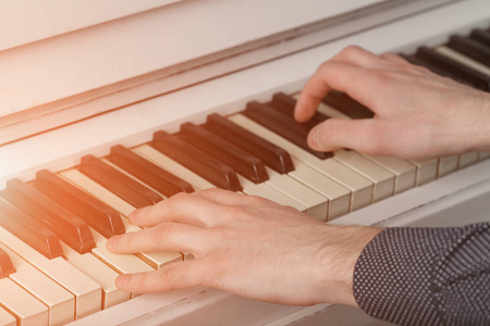 阳光与钢琴的键盘上的男人的手
