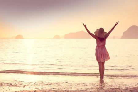 幸福的女人的帽子和短连衣裙喜欢在海上日落。出海，复古色调背景丘陵岩溶山区