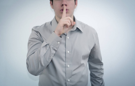 年轻男子用手指放在嘴唇上的手势嘘照片
