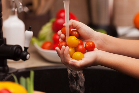 准备健康的沙拉儿童手洗樱桃西红柿
