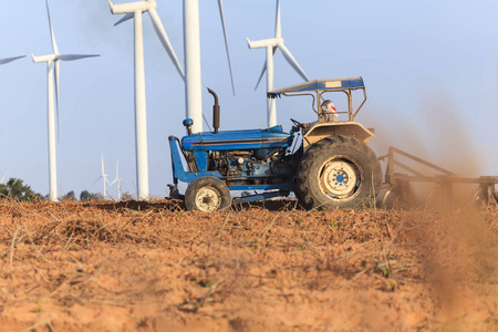 农民在拖拉机准备农田与风力涡轮发电机组