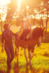 与她的母亲走附近骑在马背上的小女孩