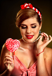 女人吃棒棒糖。Pin风格的女孩举行条纹的糖果