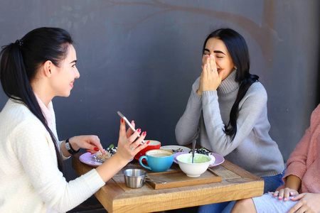 三个美丽的女人的微笑在咖啡馆,说话,告诉秘密, 吃饭,d照片